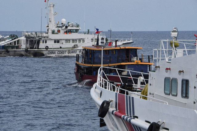 Chinese coast guard ships (L and R) corralling a Philippine civilian boat chartered by the Philippine navy to deliver supplies to the Philippine navy ship BRP Sierra Madre, in disputed waters of the South China Sea